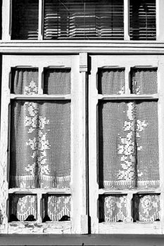 Old wooden window painted in white with crochet curtain in Porto, Portugal.