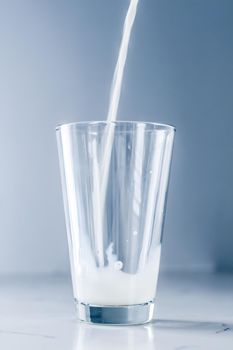 Dairy, healthy nutrition and breakfast concept - World Milk Day, pouring into glass on marble table