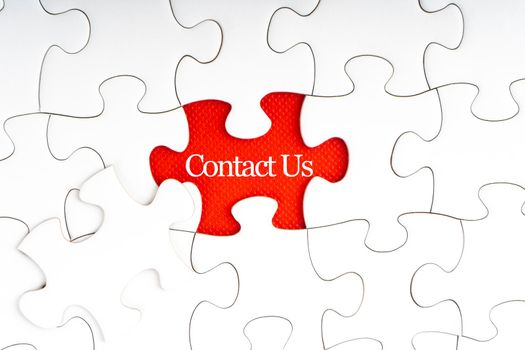 CONTACT US text with jigsaw puzzle on red background. Business and Support Concept
