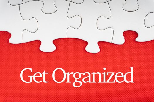 GET ORGANIZED  text with jigsaw puzzle on red background. Business and Motivation Concept