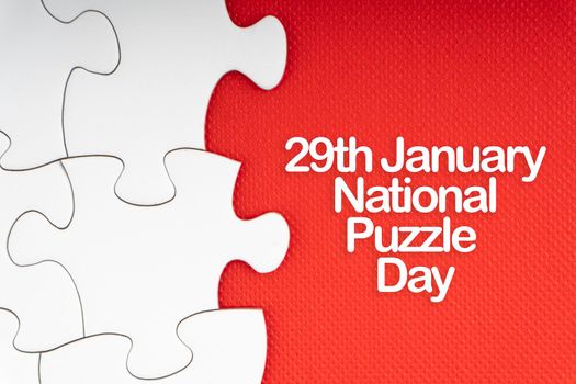 NATIONAL PUZZLE DAY  text with jigsaw puzzle on red background. Education and Holiday Concept