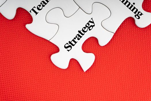 STRATEGY text with jigsaw puzzle on red background. Business and Motivation Concept