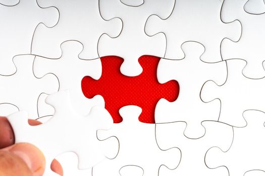Hands holding jigsaw puzzle pieces on red background. Copy space and business concept