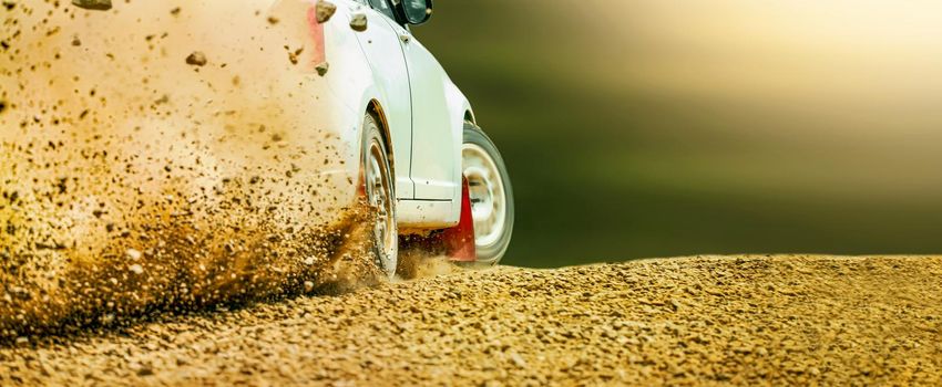 Rally race car drifting on dirt track.