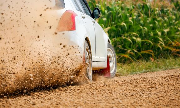 Rally race car drifting on dirt track.