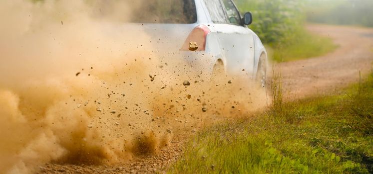 Gravel splashing from rally car drift on dirt track