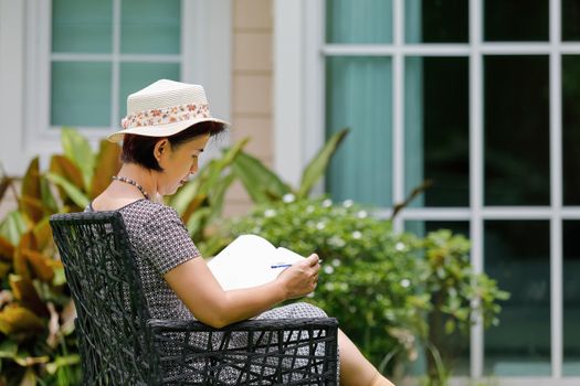 Asian middle aged female sitting relax in backyard