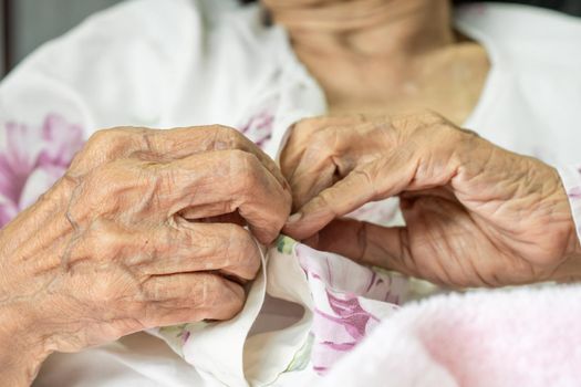 Elderly woman fasten buttons on dress , progressive brain disorder ,Close up hand