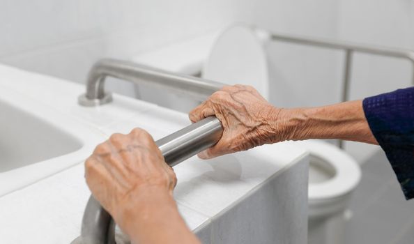 Elderly woman holding on handrail in bathroom