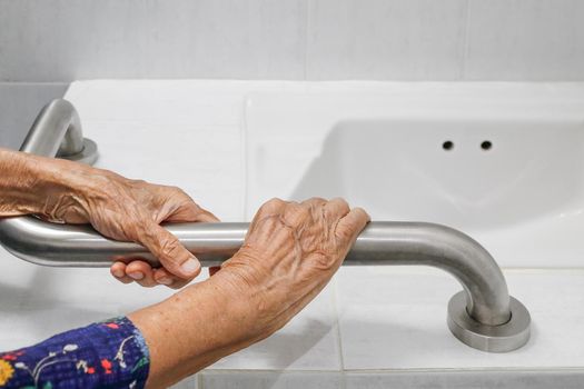 Elderly woman holding on handrail in bathroom