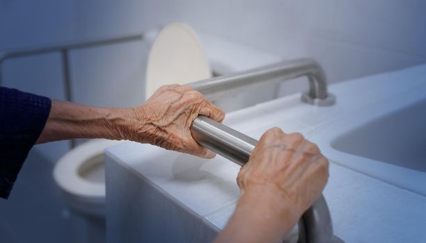 Elderly woman holding on handrail in bathroom