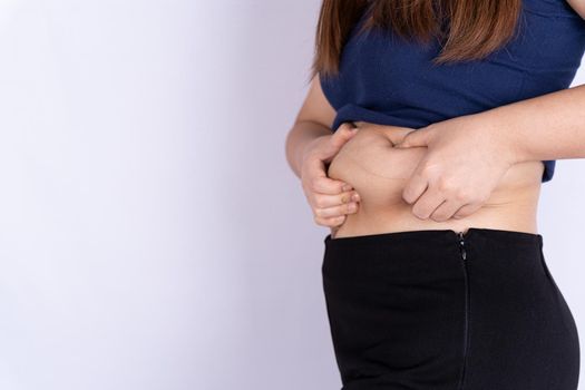 Fat woman holding excessive fat belly isolated grey background.