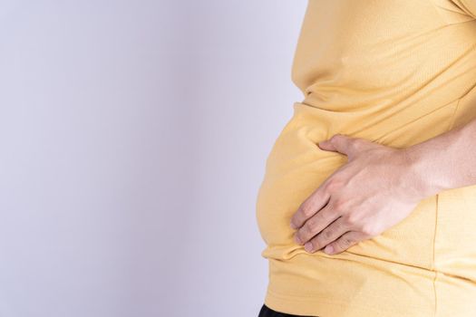 Fat man holding excessive fat belly isolated grey background.