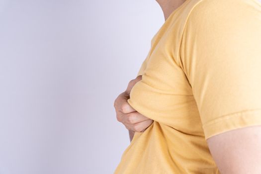 Fat man holding excessive fat boobs isolated grey background.