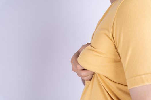 Fat man holding excessive fat boobs isolated grey background.