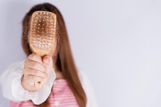 Closeup hand holding comb and hair fall problem isolated grey background.