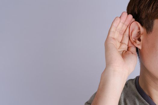 man hearing loss or hard of hearing and cupping his hand behind his ear isolate grey background, Deaf concept.