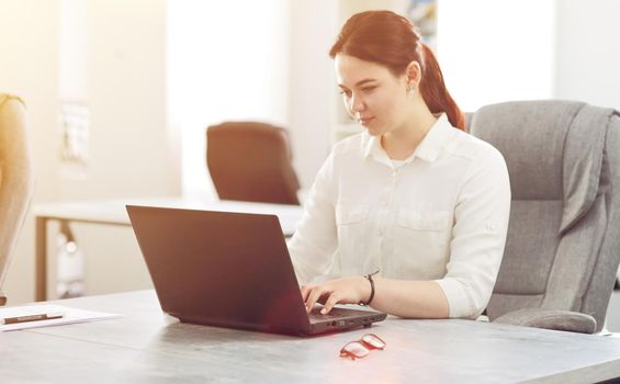 Young attractive business woman working in office smiling looking into laptop. 