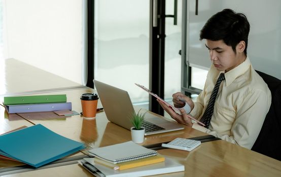 Asian business man working on documents looking concentrated with briefcase on the table