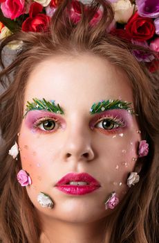 Close-up face of a beautiful girl with bright makeup. Spring flower girl. Gorgeous beauty with extended eyebrows and eyelashes. Beauty Salon Concept.