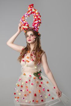 Fairy-tale girl model with floral horns. Maleficent. Spring or summer beauty. Woman in the image of a flower. Flower makeup.