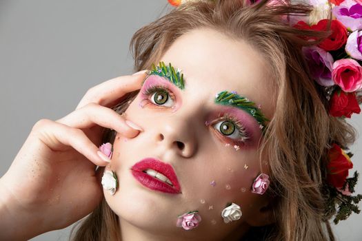 Portrait of a beautiful girl with spring make-up. Summer girl. The face of a luxurious model in flowers. The concept of eyebrow and eyelash extensions.