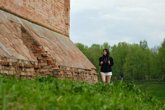 Woman walking along brick wall of a castle on a summer day.