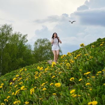 Woman walks along a path among flowers on a summer day.