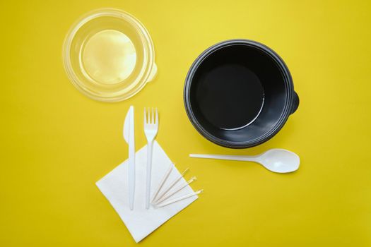 Disposable plastic tableware on yellow background. The concept of picnic utensil, environment, ecology. Top view. Selective focus. Close-up.