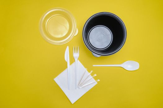 Disposable plastic tableware on yellow background. The concept of picnic utensil, environment, ecology. Top view. Selective focus. Close-up.
