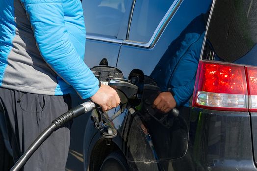 men's hand refilling the black car with a diesel with gas pump.