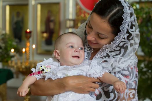 Belarus, the city of Gomil, June 20, 2019. City church.Belarus, the city of Gomil, June 20, 2019. City church. Orthodox baptism. Mother and child in a church by candlelight. Woman with a baby in the temple.