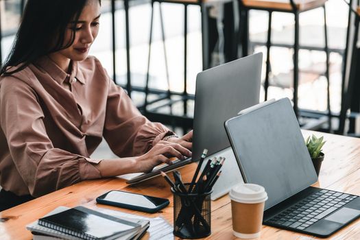 Young woman using laptop computer for business working at cafe.