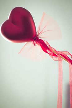 Red heart attached to a stick with a bow hanging. No people