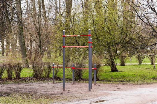 An empty gymnastic horizontal bar in a city park in early spring. Deserted city sports ground