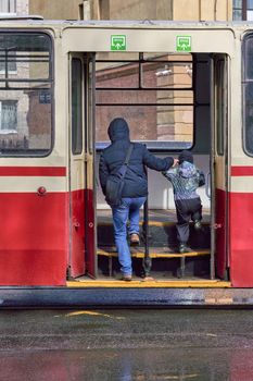 A man and a child walk through the open doors of public transport in the city.Boarding public transport. Back view