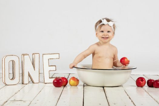 Beautiful baby bathes in a basin. One year old baby on his first birthday.