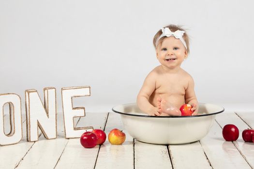Beautiful baby bathes in a basin. The child is one year old.