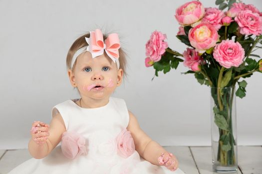 First birthday. The little girl is smeared with cream. The child is one year old.Funny child on holiday.