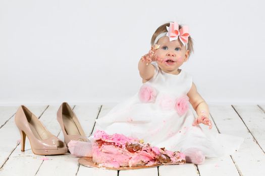 One year old child with a birthday cake. Funny little girl smeared with cream on the first anniversary. Funny child on holiday.