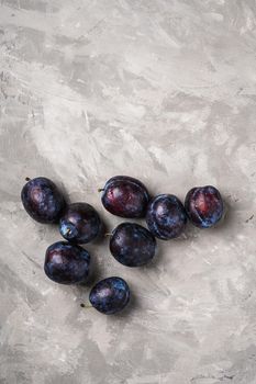 Fresh ripe plum fruits with water drops on stone concrete background, top view copy space