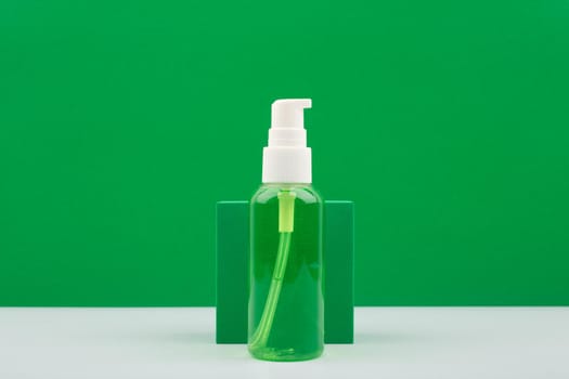 Green gel or foam for face skin cleaning on white table against green background with copy space. Concept of skin cleaning, make up removing or exfoliating