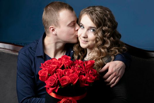 The guy and the girl with a bouquet of roses. A young couple. Lovers. A man kisses a beautiful woman.