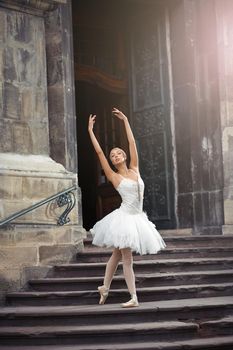 Gorgeous female ballet dancer performing outdoors dancing near and old building.