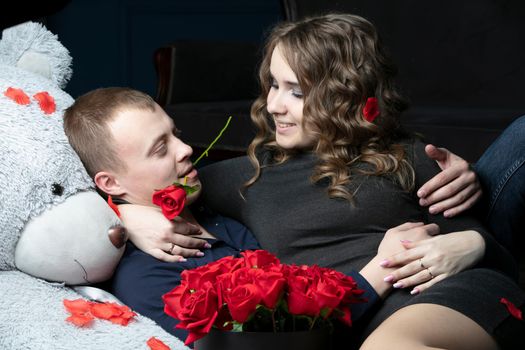 Lovers on Valentine's Day. Young couple with a soft bear and a red rose. Beautiful couple on a date.