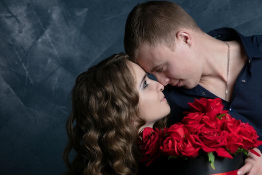 Beautiful young couple .Hugs, kisses and enjoys spending time together, celebrating Valentines Day with red roses.