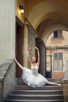 Shot of a beautiful ballerina performing outdoors dancing on the stairway of an old building doing splits grace elegance balance femininity beauty sensuality performance art.