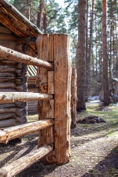 Large wooden fence posts that enclose an old wooden house in the forest. How people built houses and fences in the past. Ecological construction and materials.