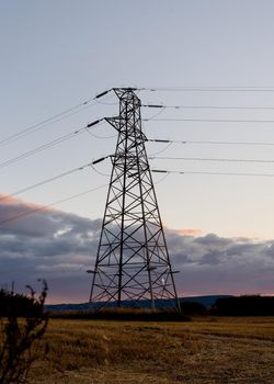 power line and electrical transmission tower or electricity pylon or power tower on field.