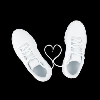 White sport shoes and heart shape from laces isolated on a black background.